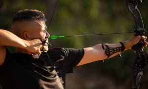 Man with prosthetic arm practicing archery with compound bow