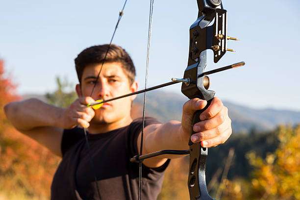 Man with prosthetic arm practicing archery with compound bow
