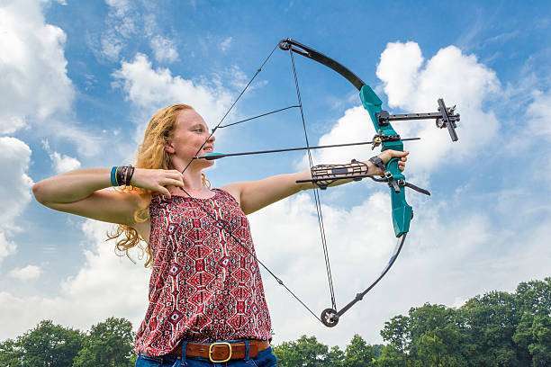 Young woman shooting archery with compound bow