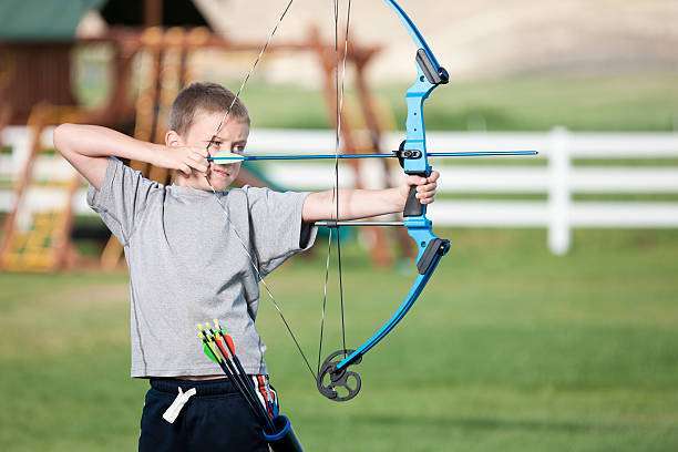 a young boy playing a compound bow