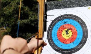 Man with prosthetic arm practicing archery with compound bow