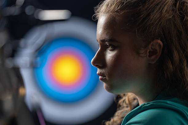 a young girl playing a compound bow