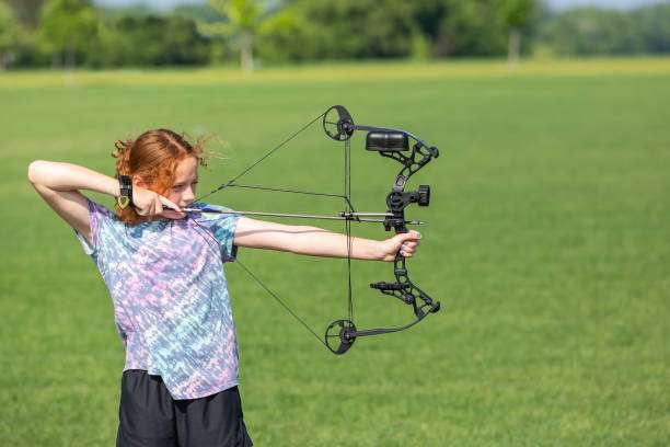 Teenage girl on archery training outdoors. Focus on the teenage girl's hands placing the arrow. playing a compound bow