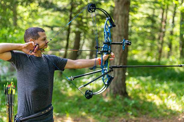 Teenage on archery training outdoors. Focus on the teenage girl's hands placing the arrow. playing a compound bow