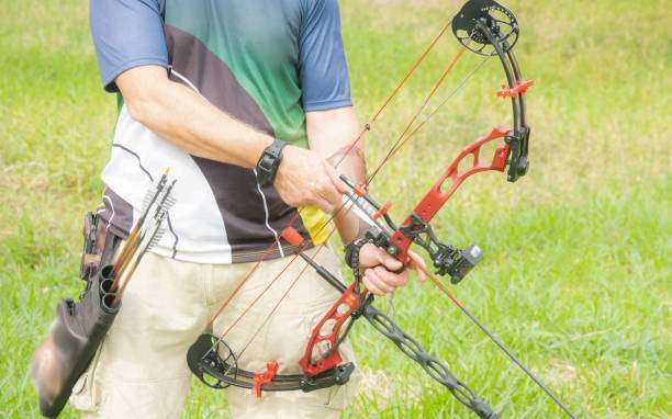Teenage girl on archery training outdoors. Focus on the teenage girl's hands placing the arrow. playing a compound bow
