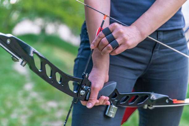 Teenage girl on archery training outdoors. Focus on the teenage girl's hands placing the arrow. playing a compound bow
