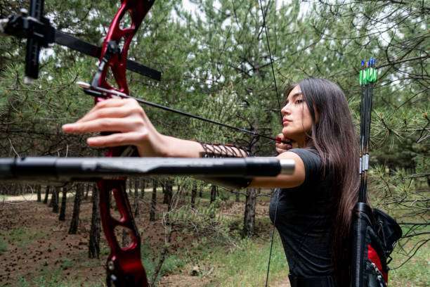 Teenage girl on archery training outdoors. Focus on the teenage girl's hands placing the arrow. playing a compound bow