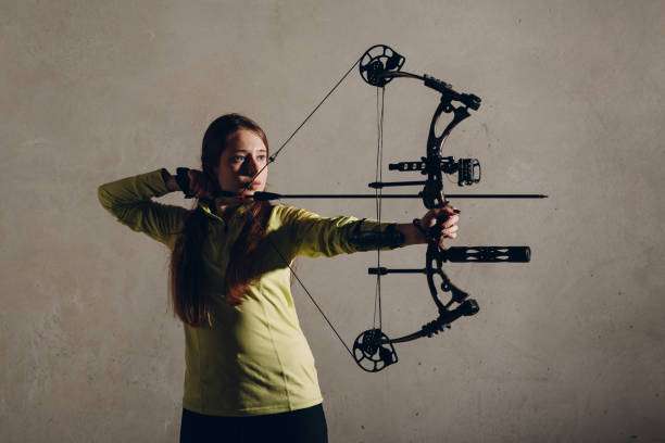 Teenage girl on archery training outdoors. Focus on the teenage girl's hands placing the arrow. playing a compound bow