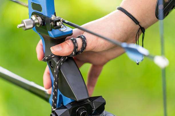 Teenage girl on archery training outdoors. Focus on the teenage girl's hands placing the arrow. playing a compound bow