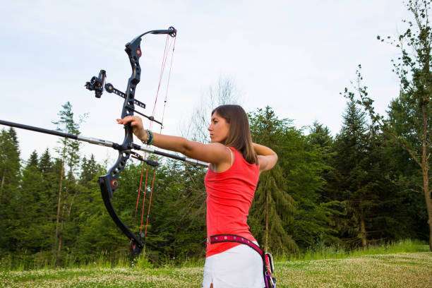 Teenage girl on archery training outdoors. Focus on the teenage girl's hands placing the arrow. playing a compound bow