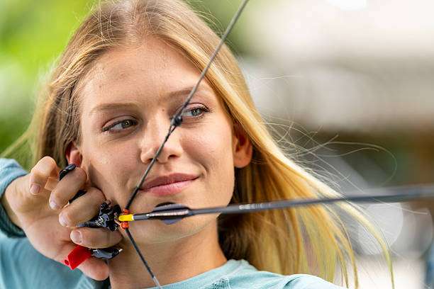 Woman aims compound bow with arrow, archery sport.