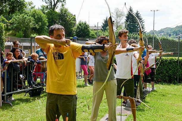 Archery group practicing in a field, preparing to use a compound bow.