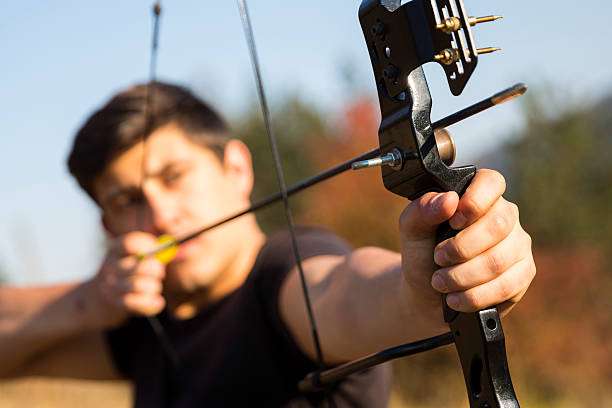 Man aiming a compound bow for target practice.