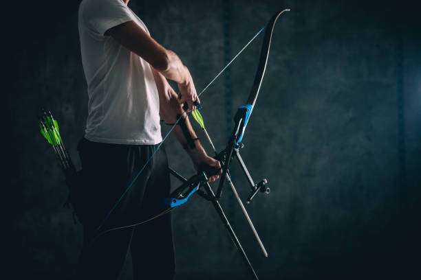 Archer in white shirt holding a modern bow, ready to shoot. Precision and power of a compound bow.