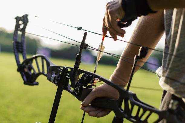 Close-up of hands loading an arrow onto a modern compound bow.