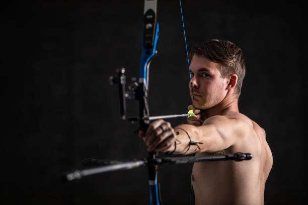 Male archer draws back a modern compound bow, ready to shoot.