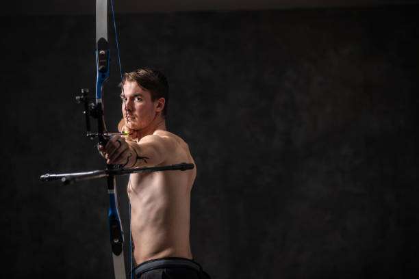 Serious and concentrated archer man with bow and arrow in hands