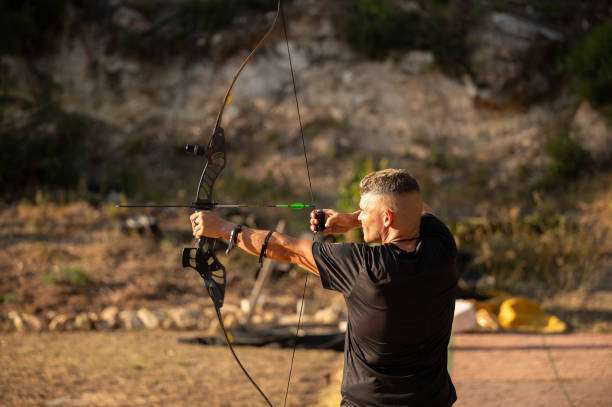 Archer takes aim with a compound bow at an outdoor range.
